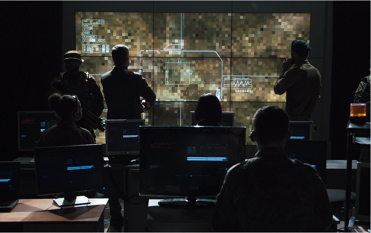 A group of people at mission control staring at a large screen