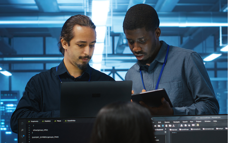 Two workers discussing the work on their laptop and tablet